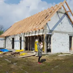 Budowa domu w stylu stodoły. Trwa montaż więźby dachowej. Cena budowy zależy od wielu czynników.