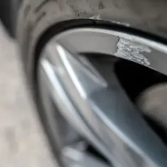 Zbliżenie na uszkodzoną, porysowaną felgę aluminiową samochodu.