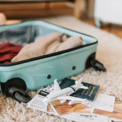 Walizka otwarta, w środku ubrania. Obok paszport, bilety i model samolotu. Czekamy na lot z Electra Airways, opinie są różne.