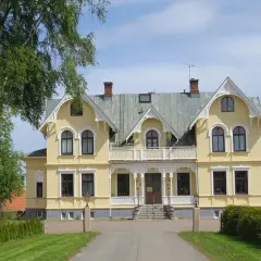 Gult hus med vita detaljer, en vacker entré och grönska. Perfekt för en Scandic Billingen frukost.