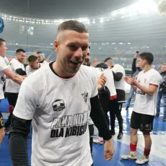 Piłkarze w białych koszulkach z napisem "Piłka nożna dla kibiców" świętują. To obraz z historii tabeli wszechczasów ekstraklasy.