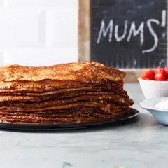 En hög med gyllene pannkakor, redo att avnjutas med jordgubbar och grädde. Perfekt för ett enkelt pannkakssmet recept. MUMS!