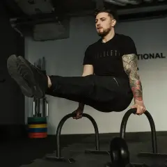 Mężczyzna wykonuje ćwiczenie na poręczach, pokazując, jak połączyć crossfit z siłownią.
