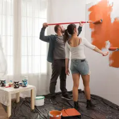Para maluje ścianę na pomarańczowo, tworząc ciekawe wzory.