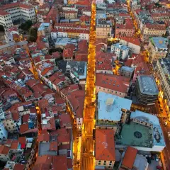 Widok z lotu ptaka na miasto z czerwonymi dachami, oświetloną ulicą i widokiem na morze. To jakby być na festiwalu San Remo, czuć atmosferę.