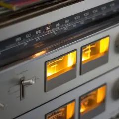 Klasy wzmacniaczy w retro sprzęcie audio. Wskaźniki VU świecą na pomarańczowo, a tuner pokazuje częstotliwość 94 MHz.