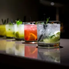 Rząd kolorowych, prostych drinków z wódką, z lodem i miętą, gotowych do podania.