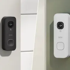 Dos tipos de videoporteros Blink, uno negro y otro blanco, instalados en paredes exteriores.