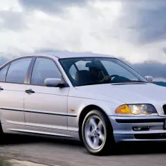 Un BMW 320d E46 150cv Stage 2 plateado circula por una carretera rural.