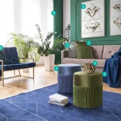Salon z kanapą, fotelami i pufami. Ściany w kolorze głębokiej zieleni, z obrazami przedstawiającymi diamenty. Wnętrze zdobią rośliny i tekstylia w odcieniach niebieskiego i **kolor szmaragdowy**.