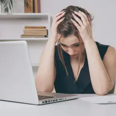 Zrozpaczona kobieta przy laptopie, martwiąca się o pko bp śmierć współwłaściciela konta.
