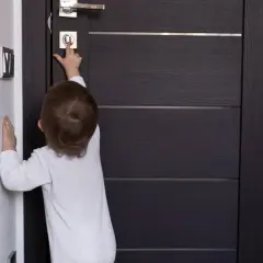 Dziecko próbuje dowiedzieć się, jak zablokować drzwi od wewnątrz, naciskając przycisk na zamku.
