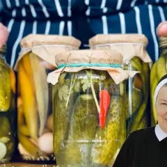 Słoiki z ogórkami i przyprawami, gotowe do przetworzenia. Siostra zakonna uśmiecha się, sugerując, że to jej sekretny pikle przepis.