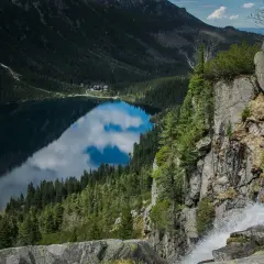 Widok na Morskie Oko z góry, z wodospadem po prawej. Trasa turystyczna prowadzi wzdłuż jeziora otoczonego lasem i górami.