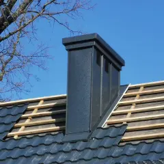 Nowy komin na dachu, widoczne łaty i kontrłaty pod dachówką.