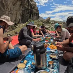 Grupa ludzi podczas posiłku na świeżym powietrzu, przygotowująca się do trekkingu pod K2.