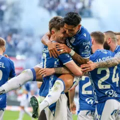 Piłkarze Lecha Poznań w niebieskich strojach świętują zwycięstwo, przytulając się na boisku.