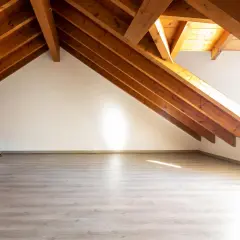 Jasne, przestronne wnętrze z drewnianymi belkami stropowymi i jasną podłogą. To **inaczej poddasze**, gotowe na nowe aranżacje.