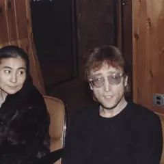 John Lennon i Yoko Ono siedzą w studiu. Yoko w czarnym futrze, John w okularach.