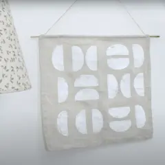Idée tableau peinture à faire soi-même : tissu beige orné de formes géométriques blanches, style moderne et épuré.