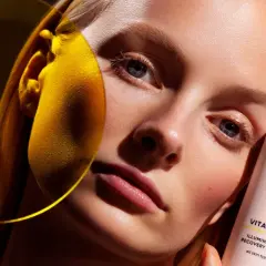 Strahlende Haut dank Vitamin C Skin Care. Eine Frau hält eine Flasche MÁDARA Illuminating Recovery Cream.