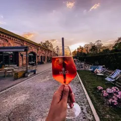 Nietypowe restauracje Warszawa: drink w ręce, ceglany budynek i ogród z leżakami. Idealne miejsce na relaks.