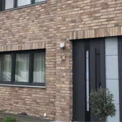 Nowoczesne drzwi zewnętrzne i okno na ceglanej ścianie domu.