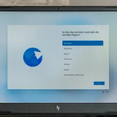 Ein Laptop zeigt die Windows 11 Einrichtung mit der Länderauswahl. Hier kann man Windows 11 ohne Microsoft Konto einrichten, indem man Deutschland wählt.