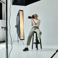 Młody fotograf w studio, z aparatem w ręku, zastanawia się, ile zarabia fotograf.