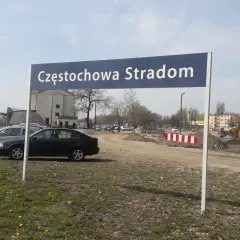 Tablica z napisem Częstochowa Stradom. W tle budynki, tory kolejowe i samochody.