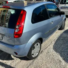 Ford Fiesta 1.4 TDCI con algunos problemas visibles, aparcado sobre grava.