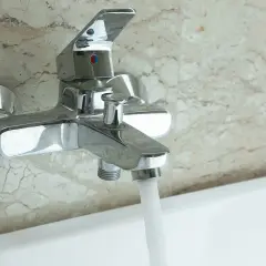 Robinet de baignoire mural chromé, prêt à installer, avec eau coulant doucement.
