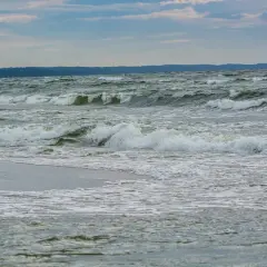 Fale rozbijają się o brzeg. Zastanawiasz się, co robić zimą nad morzem? Spacer po plaży i podziwianie żywiołu to świetny pomysł.