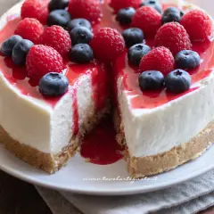 Cheesecake ricetta: torta cremosa con base croccante, guarnita con lamponi, mirtilli e coulis rosso.