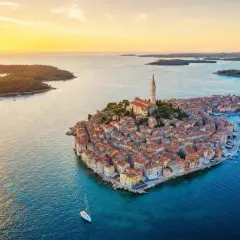 Zachód słońca nad malowniczym Rovinj w Chorwacji. Miasto z charakterystyczną wieżą kościelną, otoczone turkusowym morzem i zielonymi wyspami.