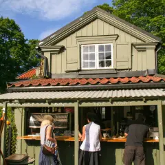 Vid Waldemarsudde café beställer folk fika i solen.