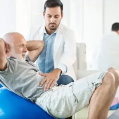Un homme âgé fait des exercices avec un kinésithérapeute pour traiter l'incontinence urinaire chez l'homme.