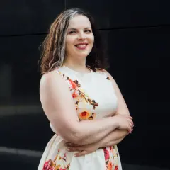 Uśmiechnięta kobieta w kwiecistej sukience, szukająca tanich sukienek plus size na wesele.