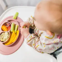 Dziecko odkrywa smaki warzyw, stosując metodę blw. Na talerzyku: pomidorki, ogórek, papryka i pasta.