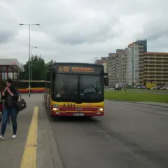 Autobus linii 518 w Warszawie czeka na pasażerów na przystanku. W tle widać blokowiska.