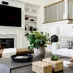 Stylish coffee table decor ideas: woven boxes, a black tray with a magazine, and a large vase with greenery.