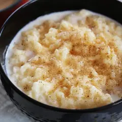 Un tazón negro lleno de cremosas gachas de arroz, espolvoreadas con canela.