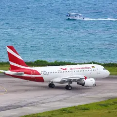 Samolot Air Mauritius na pasie startowym, w tle turkusowe morze i łódź. Czas dowiedzieć się, ile się leci na Mauritius!