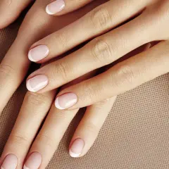 Dłonie z perfekcyjnym manicurem w stylu kok francuski. Delikatny róż i białe końcówki paznokci.