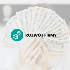 Dłoń trzyma wachlarz banknotów dolarowych z ikoną i napisem "ROZWÓJ FIRMY".
