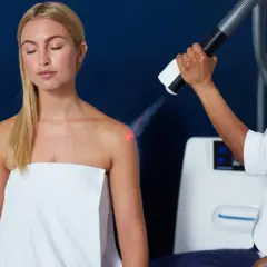 Krioterapia miejscowa: blondynka z zamkniętymi oczami poddaje się zabiegowi chłodzenia na ramieniu.