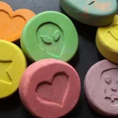 Kolorowe tabletki z symbolami: serce, uśmiech, czaszka, gwiazda, kosmita. To mogą być tabletki MDMA.