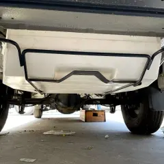Vue sous un camping-car, montrant le réservoir d'eau propre fixé au châssis. Préparation pour le nettoyage de la cuve camping car.