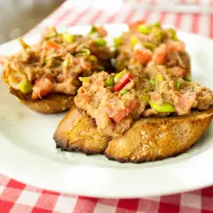 Trzy chrupiące kromki chleba z pastą z tuńczyka, pomidorów i zielonej cebulki. Idealna bruschetta z tuńczykiem na letni obiad.