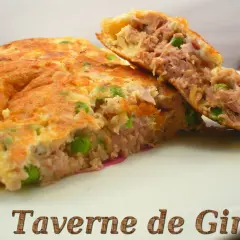 Une omelette au thon généreuse, garnie de petits pois, coupée en deux pour révéler sa texture moelleuse. Un délice simple et savoureux.